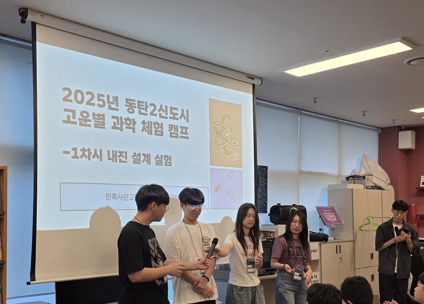 Student volunteers presenting at a science camp in front of a slide about earthquake-resistant design